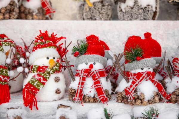 A picture of miniature snowman with red hats and scarves and snow on the ground